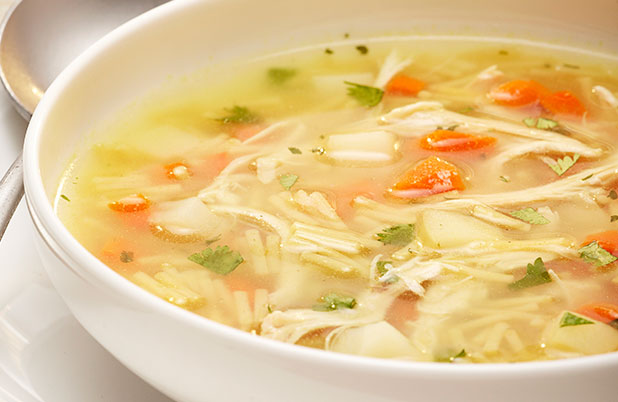 A bowl of vegetable soup with thin noodles and cilantro.