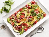 Ceviche de lenguado con pepino, tomate, cilantro y aguacate en un tazón redondo en una mesa rústica con aguacates y limones.