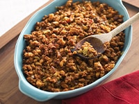 Relleno de chorizo mexicano en un plato azul con una cuchara dentro, sobre una superficie de madera.