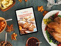 Libro de recetas de Acción de Gracias en iPad sobre una mesa de madera rodeada de pavo y acompañamientos.