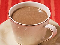 Cup of hot Pumpkin & ABUELITA Atole on saucer with seamless red background.