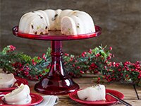 Christmas Punch Gelatin on vintage red colored glass cake stand on table with holly and berries.