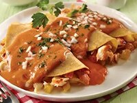 Enchiladas de Pescado al Pastor en un Plato Blanco y Servilleta Roja sobre una Superficie Verde.